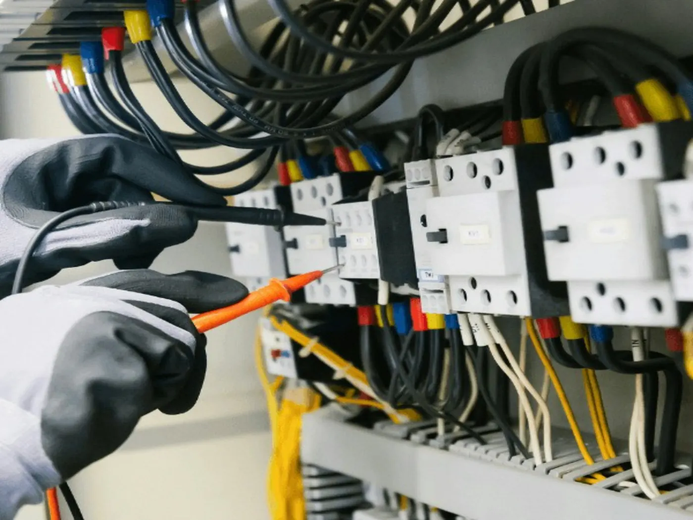 Električar z merilnikom preverja vezavo v elektro omari
